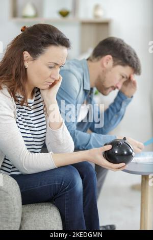 un homme et une femme concentrés sont assis sur un canapé et ont des problèmes financiers Banque D'Images