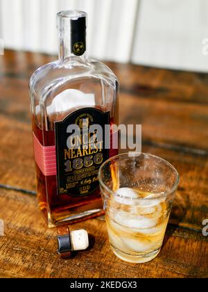 Oncle le plus proche, plateau supérieur, bouteille de whisky Tennessee bourbon à côté d'un verre de bourbon, sur glace sur une table. Banque D'Images