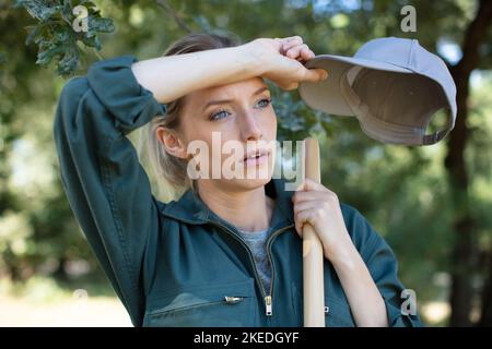 jeune femme fatiguée avec des outils de jardin Banque D'Images