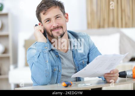 homme au téléphone pendant l'installation du mobilier Banque D'Images