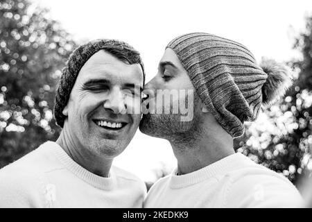 Heureux mature gay hommes couple prenant selfie embrassant en hiver en plein air - LGBTQ amour concept - noir et blanc montage Banque D'Images