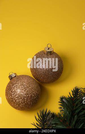 boules décoratives de Noël dorées sur fond jaune avec pin vert Banque D'Images