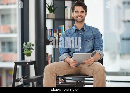 L'avenir semble radieux de l'endroit où la messagerie instantanée est assise. Portrait court d'un homme d'affaires créatif travaillant sur sa tablette dans son bureau. Banque D'Images