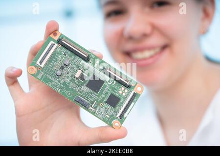 jeune assistante de laboratoire tenant un prototype de carte de circuit imprimé pour un dispositif de commande de système d'énergie solaire Banque D'Images