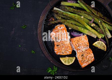 Délicieux saumon cuit avec asperges, tranches de citron et épices sur table sombre. Vue de dessus, plan d'appartement Banque D'Images