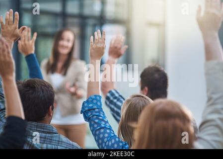 Atelier au bureau. Un groupe de personnes levant la main dans un séminaire. Banque D'Images