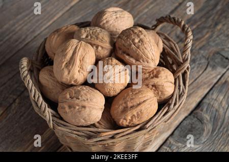 Noix dans un ancien panier en osier sur une table en bois rustique en gros plan Banque D'Images