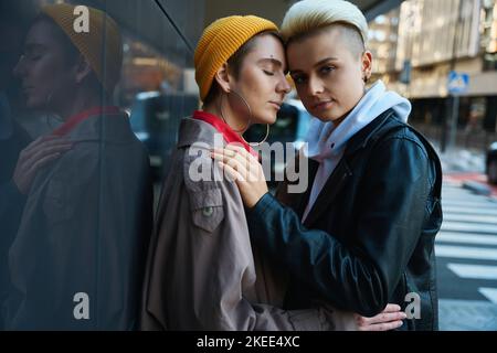 Deux femmes s'embrassant dans la rue de la ville à proximité de bâtiments modernes Banque D'Images