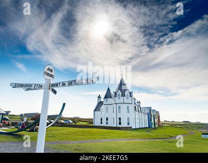 John O Groats, Caithness, Scotland-29 juillet 2022 : l'emblématique enseigne blanche multidirectionnelle se trouve en face de la résidence victorienne historique, Banque D'Images