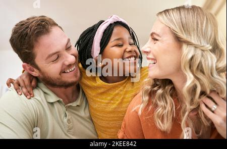 Diversité familiale et adoption avec une mère nourricier, un père et une fille qui se nouent dans le salon de leur maison. Confiance, amour et sourire avec un homme, une femme Banque D'Images