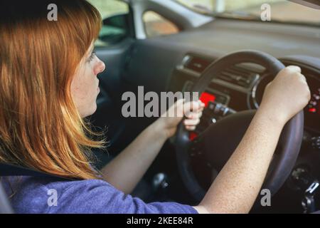 Une jeune femme qui conduit une voiture se concentrait sur la route qui l'attend. Banque D'Images