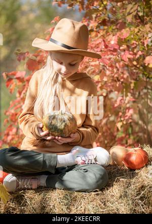 Petites filles assises parmi les balles de foin et les citrouilles dans le jardin d'automne Banque D'Images