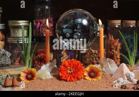 Boule de cristal avec bougies et pierres de chakra sur le sable rouge australien Banque D'Images