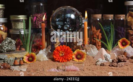 Boule de cristal avec bougies et pierres de chakra sur le sable rouge australien Banque D'Images