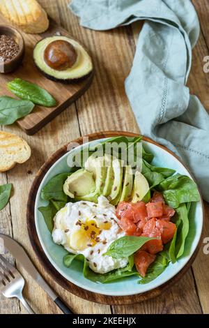 Cétogène, céto ou paléorégime. Délicieux petit déjeuner ou bol à déjeuner avec saumon salé, avocat, œuf dur et épinards sur une table rustique. Banque D'Images