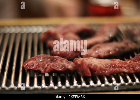 Petits morceaux de bœuf cru rouge cuisant sur barbecue en métal Banque D'Images