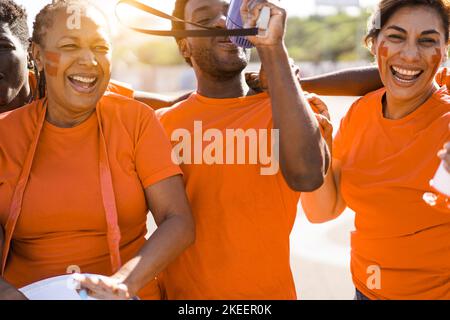 Les fans de sport Orange crient tout en soutenant leur équipe - les supporters de football s'amusent lors d'un événement de compétition - concentrez-vous sur l'œil gauche de l'homme africain Banque D'Images