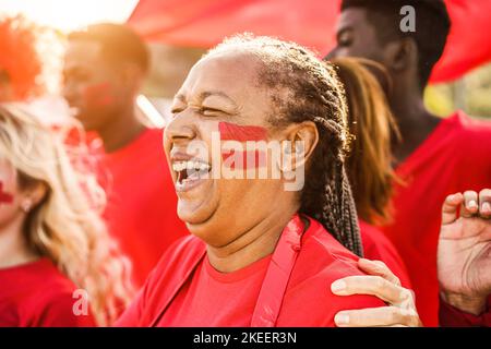 Les fans de sport rouge africains crient tout en soutenant leur équipe - les supporters de football s'amusent lors d'un événement de compétition - concentrez-vous sur le visage des femmes âgées Banque D'Images