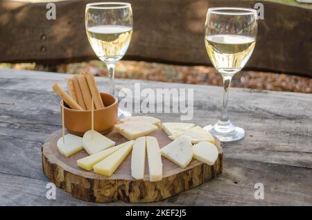 Dégustation de fromage de chèvre et de vin blanc sur une planche de bois. Banque D'Images