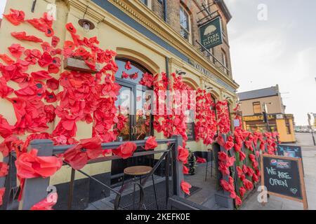 Southend on Sea, Royaume-Uni. 12 novembre 2022. Extérieur du pub Park Tavern décoré de grands coquelicots rouges sur filet vert en commémoration du jour du souvenir. Le bâtiment en briques de deux étages présente des fenêtres cintrées et une architecture traditionnelle. Des panneaux de tableau noir sont placés sur le trottoir, contribuant ainsi à l'affichage axé sur la communauté. Penelope Barritt/Alamy Live News Banque D'Images