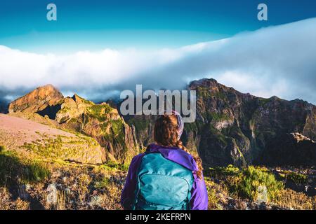 Description: Randonneur regardant le beau paysage de montagne de Pico Ruivo dans la matinée. Pico do Arieiro, île de Madère, Portugal, Europe. Banque D'Images