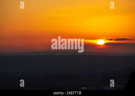 Halifax, Calvaire, West Yorkshire, Royaume-Uni. 12th novembre 2022. Météo Royaume-Uni. Un magnifique lever de soleil au-dessus des collines de Pennine du West Yorkshire, au-dessus de la ville de Halifax, à Calvaire, vue depuis le sommet de la colline près de Queensbury. Sur l'horizon se trouvent des silhouettes lointaines de moulins à vent. Crédit : Windmill Images/Alamy Live News Banque D'Images