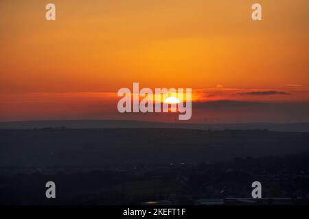 Halifax, Calvaire, West Yorkshire, Royaume-Uni. 12th novembre 2022. Météo Royaume-Uni. Un magnifique lever de soleil au-dessus des collines de Pennine du West Yorkshire, au-dessus de la ville de Halifax, à Calvaire, vue depuis le sommet de la colline près de Queensbury. Sur l'horizon se trouvent des silhouettes lointaines de moulins à vent. Crédit : Windmill Images/Alamy Live News Banque D'Images