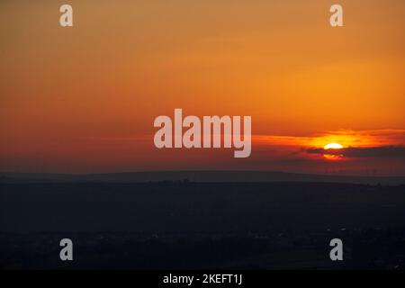 Halifax, Calvaire, West Yorkshire, Royaume-Uni. 12th novembre 2022. Météo Royaume-Uni. Un magnifique lever de soleil au-dessus des collines de Pennine du West Yorkshire, au-dessus de la ville de Halifax, à Calvaire, vue depuis le sommet de la colline près de Queensbury. Sur l'horizon se trouvent des silhouettes lointaines de moulins à vent. Crédit : Windmill Images/Alamy Live News Banque D'Images