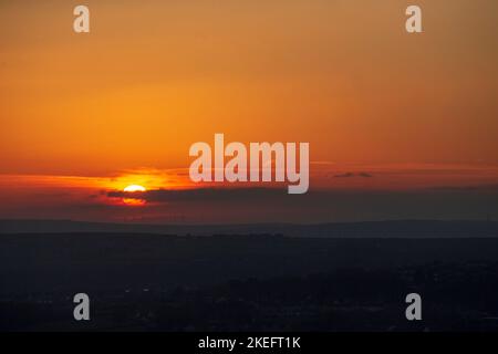 Halifax, Calvaire, West Yorkshire, Royaume-Uni. 12th novembre 2022. Météo Royaume-Uni. Un magnifique lever de soleil au-dessus des collines de Pennine du West Yorkshire, au-dessus de la ville de Halifax, à Calvaire, vue depuis le sommet de la colline près de Queensbury. Sur l'horizon se trouvent des silhouettes lointaines de moulins à vent. Crédit : Windmill Images/Alamy Live News Banque D'Images