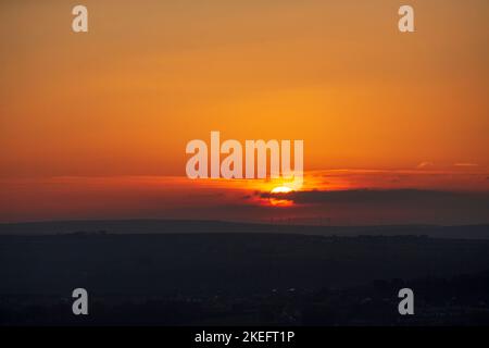 Halifax, Calvaire, West Yorkshire, Royaume-Uni. 12th novembre 2022. Météo Royaume-Uni. Un magnifique lever de soleil au-dessus des collines de Pennine du West Yorkshire, au-dessus de la ville de Halifax, à Calvaire, vue depuis le sommet de la colline près de Queensbury. Sur l'horizon se trouvent des silhouettes lointaines de moulins à vent. Crédit : Windmill Images/Alamy Live News Banque D'Images