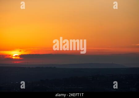 Halifax, Calvaire, West Yorkshire, Royaume-Uni. 12th novembre 2022. Météo Royaume-Uni. Un magnifique lever de soleil au-dessus des collines de Pennine du West Yorkshire, au-dessus de la ville de Halifax, à Calvaire, vue depuis le sommet de la colline près de Queensbury. Sur l'horizon se trouvent des silhouettes lointaines de moulins à vent. Crédit : Windmill Images/Alamy Live News Banque D'Images