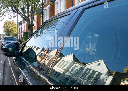 Londres, Royaume-Uni, 12 novembre 2022 : sur Hambalt Road, dans la zone du village d'Abbeville à Clapham, une rangée de maisons mitoyennes au soleil éclatant se reflète dans la fenêtre d'une voiture de sport. Les prix de la maison Clapham sont élevés et de nombreuses voitures de luxe sont garées dans les rues. Anna Watson/Alay Live News Banque D'Images
