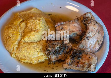 viande de lapin avec polenta. porridge de maïs local avec morceaux de ragoût de lapin. Mise au point sélective avec faible profondeur de champ. Cuisine italienne traditionnelle. Banque D'Images