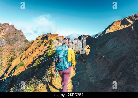 Description: Femme randonnée le long du sentier de randonnée pittoresque jusqu'à Pico Ruivo le matin. Pico do Arieiro, île de Madère, Portugal, Europe. Banque D'Images