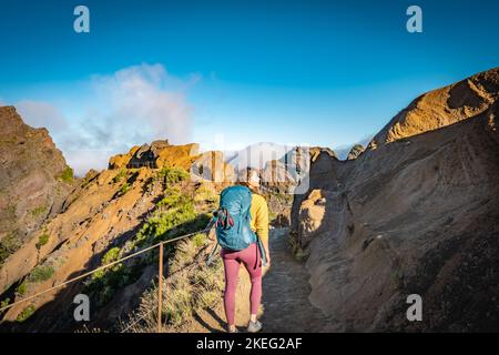 Description: Femme randonnée le long du sentier de randonnée pittoresque jusqu'à Pico Ruivo le matin. Pico do Arieiro, île de Madère, Portugal, Europe. Banque D'Images