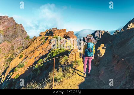 Description: Femme randonnée le long du sentier de randonnée pittoresque jusqu'à Pico Ruivo le matin. Pico do Arieiro, île de Madère, Portugal, Europe. Banque D'Images