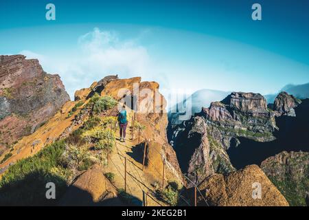 Description: Femme randonnée le long du sentier de randonnée pittoresque jusqu'à Pico Ruivo le matin. Pico do Arieiro, île de Madère, Portugal, Europe. Banque D'Images