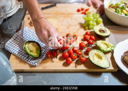 Homme cueillant à la main des tomates cerises pour sa préparation de petit-déjeuner Banque D'Images