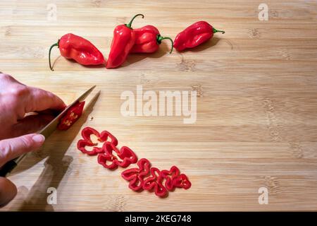 Capsicum chinense 'Scotch Bonnet' étant tranché sur une table en bois Banque D'Images