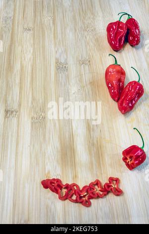 Capsicum chinense 'Scotch Bonnet' entier et tranché sur une table en bois Banque D'Images