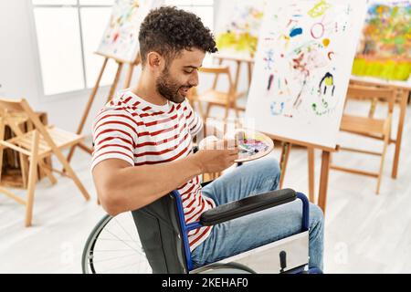 Jeune artiste arabe handicapé homme de dessin assis sur un fauteuil roulant dans un studio d'art. Banque D'Images