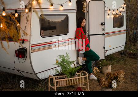 Une femme caucasienne en pull tricoté rouge surdimensionné voyage à motorhome en automne. Banque D'Images