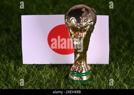 13 novembre 2022, Doha, Qatar. Trophée de la coupe du monde de la FIFA sur fond de drapeau japonais sur la pelouse verte du stade. Banque D'Images