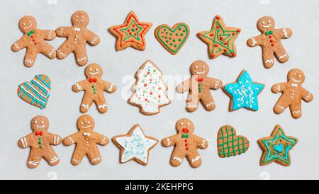 Biscuits de Noël sur fond gris. Biscuits au gingembre faits maison avec glaçage coloré. Homme de pain d'épice, étoile et arbre de Noël. Vue de dessus, plan d'appartement. Banque D'Images
