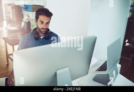 Axé sur la tâche immédiate. Photo en grand angle d'un beau jeune homme d'affaires travaillant sur son ordinateur au bureau. Banque D'Images