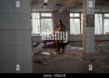 Après la fin de la période nucléaire, la vie est apocalyptique. Une femme grimy survivante lisant dans un bâtiment abandonné Banque D'Images