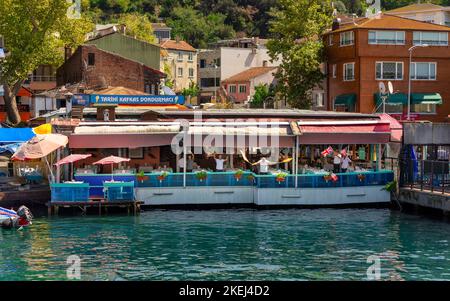 Istanbul, Turquie - 29 août 2022 : tiré du ferry du personnel flottant du restaurant qui agite des drapeaux et danse pour accueillir les visiteurs du quartier d'Anadolu Kavagi, sur le côté asiatique du détroit du Bosphore Banque D'Images