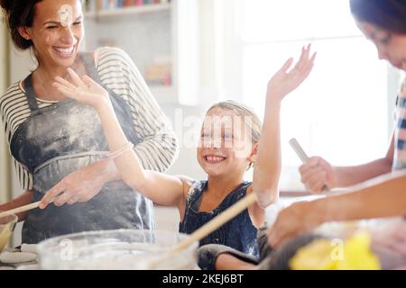 Amusement pour toute la famille. Deux petites filles s'amusant tout en cuisant avec leur mère dans la cuisine. Banque D'Images