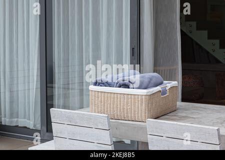 Serviettes de bain bleues dans un panier en osier sur une table en béton dans un jardin ensoleillé Banque D'Images