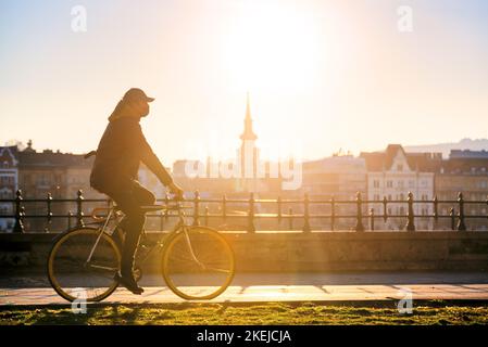 Cycliste au coucher du soleil sur les gratte-ciel de la vieille ville Banque D'Images